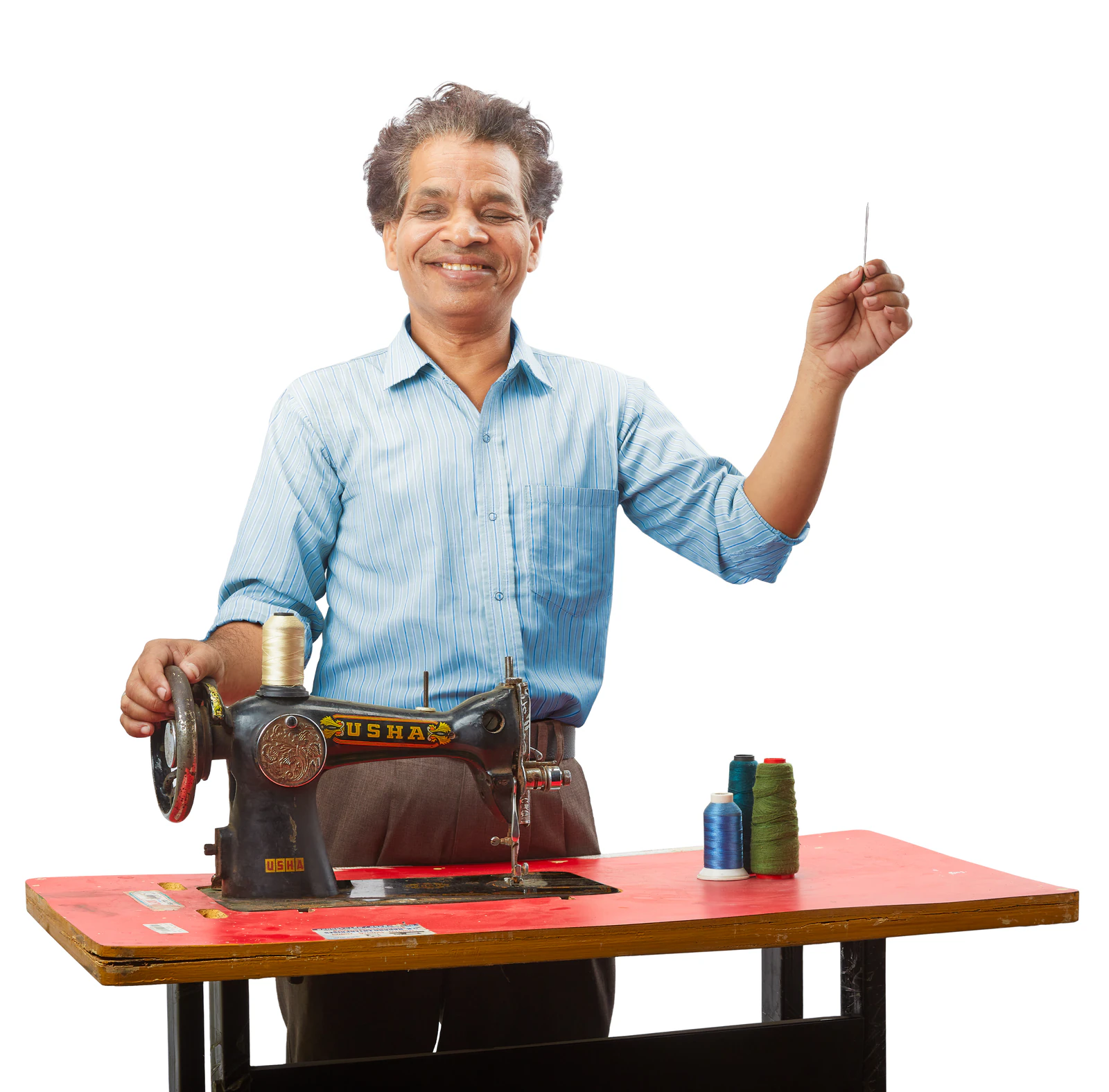 Rajesh smiling and holding up a needle while working at a sewing machine